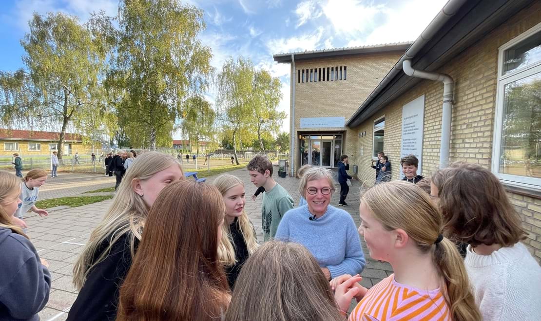 Underviser og elever griner sammen på legepladsen